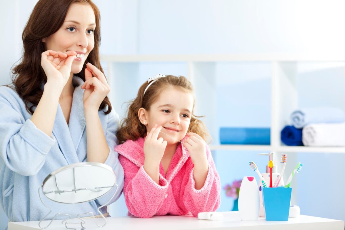 Personas usando hilo dental, para completar su rutina de limpieza dental